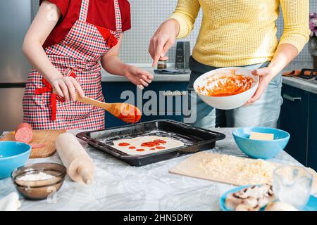 Zwei Frauen bereiten gemeinsam in der Küche Essen zu. Nahaufnahme der Hände. Das Konzept der hausgemachten Speisen. Stockfoto