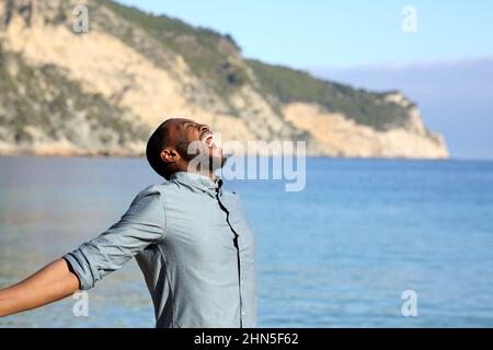 Profil eines aufgeregten Mannes mit schwarzer Haut, der seinen Urlaub am Strand feiert Stockfoto