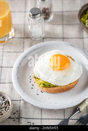 Toast mit Spiegelei und Avocado-Sauce auf einem Teller, gesundes Frühstücksmenü-Konzept Stockfoto