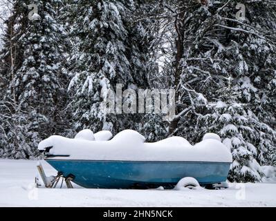 Blue Fishing Boat auf Anhänger für den Winter ist mit Schnee bedeckt Stockfoto