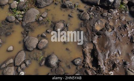 Ein Weg in den Schlamm und Pfützen auf der schmutzigen Straße. Schlammpfützen nach Regen, schmutziger Boden. Stockfoto