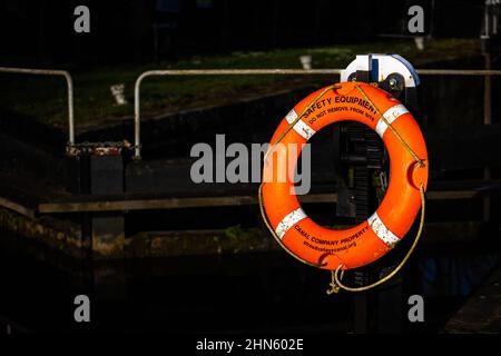 Leuchtender orangefarbener Rettungsring auf einer Kanalschleuse in der Nähe von Stonehouse, Großbritannien Stockfoto