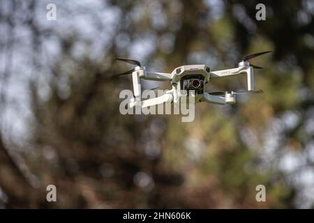 Eine Drohne des DJI Mini 2 schwebt vor einem unfokussierten Hintergrund in der Luft, England Stockfoto