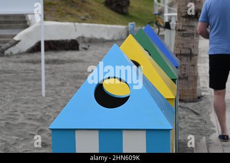 Eine Reihe von Recyclingbehältern an einem Strand in Costa Adeje, Teneriffa, die in Blau-, Gelb- und Grüntönen Zelten ähneln Stockfoto