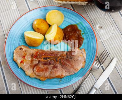 Gebratenes Schweinefleisch auf Knochen mit gekochten Kartoffeln in ihren Häuten Stockfoto