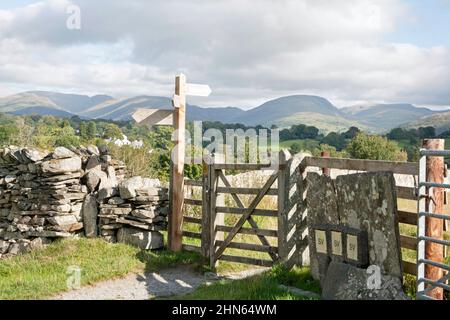 Fußwegschild und Tor, das nach St. Michael und alle Angels Church Hawkshead der Lake District Cumbria England führt Stockfoto