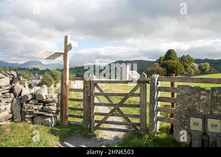 Fußwegschild und Tor, das nach St. Michael und alle Angels Church Hawkshead der Lake District Cumbria England führt Stockfoto