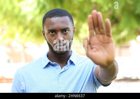 Vorderansicht Porträt eines wütenden schwarzen Mannes beim Stopschild in einem Park Stockfoto