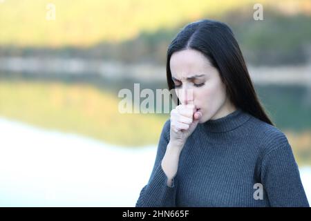 Frau, die im Winter mit der Hand in der Natur hustet Stockfoto