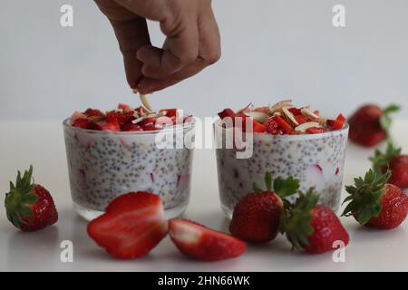 Hafer mit Chiasamen und Erdbeeren über Nacht. Ein gesundes Frühstück. Schuss mit vielen Erdbeeren auf weißem Backgroun Stockfoto