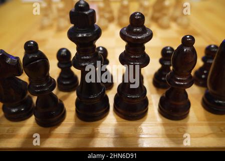 Schwarze Schachfiguren vor weißen Stockfoto
