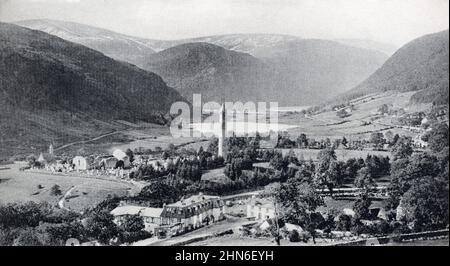 Eine historische Ansicht von Glendalough County Wicklow, Irland. Der imposante runde Turm befindet sich in der Mitte, mit anderen Sehenswürdigkeiten wie der St. Kevin's Church ist sichtbar. Ca. 1920s. Stockfoto