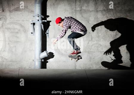 Skateboarder unter Überführung mit Schatten an der Wand Stockfoto