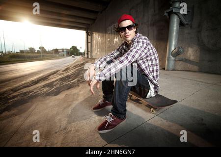 Skateboarder sitzt unter der Überführung an Bord Stockfoto