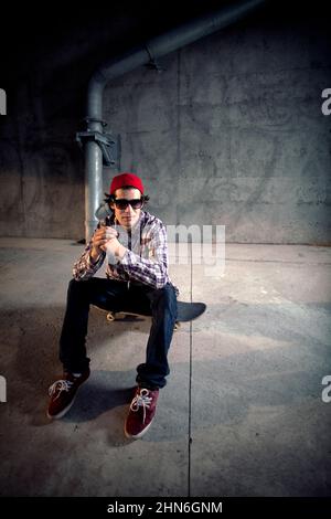 Skateboarder sitzt unter der Überführung an Bord Stockfoto