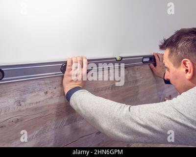 caen, frankreich Februar 2022. Ein Tischler überprüft den Füllstand mit einer Wasserwaage in der Küchentheke. Professionelle Möbelmontage in der Küche Stockfoto