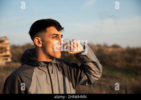 Nahaufnahme eines jungen Mannes, der im Freien ein Marihuanagelenk raucht Stockfoto