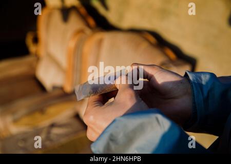 Nahaufnahme der Hände eines Jungen, die ein Marihuanagelenk im Freien Rollen Stockfoto