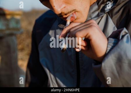 Nahaufnahme eines jungen Mannes, der im Freien ein Marihuanagelenk raucht Stockfoto