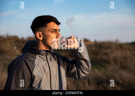 Nahaufnahme eines jungen Mannes, der im Freien ein Marihuanagelenk raucht Stockfoto