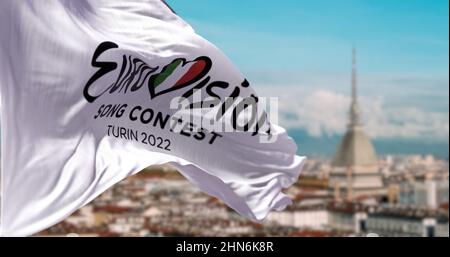 Turin, Italien, Januar 2022: Die weiße Flagge mit dem Logo des Eurovision Song Contest 2022 winkt im Wind mit der verschwommenen Landschaft von Turin. Stockfoto