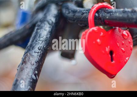 Herzförmiges Liebe-Vorhängeschloss mit Regentropfen in der Nahaufnahme. Stockfoto