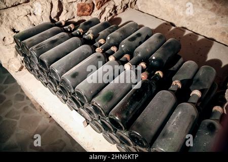 Weinflaschen, die in einem Weinkeller auf einem Weingut mit Staub bedeckt sind. Weinindustrie in Europa Stockfoto