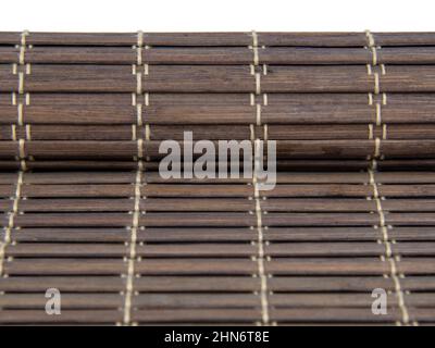 Gerollte Bambusmatte für Lebensmittel dunkle Farbe isoliert auf dem weißen Hintergrund Stockfoto