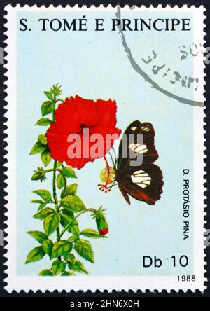 SAO TOME UND PRINCIPE - UM 1988: Eine in Sao Tome und Principe gedruckte Briefmarke zeigt einen dunkelbraunen und weißen Schmetterling und eine rote Blume, um 1988 Stockfoto