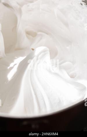 Geschlagene Eiweiß - italienische Baiser in einer Schüssel mit Mixer, Nahaufnahme und Platz zum Kopieren. Stockfoto