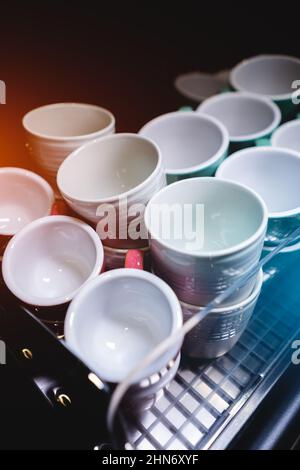 Set aus Keramikbechern oder Tassen, die auf einer professionellen Kaffeemaschine erhitzt werden Stockfoto