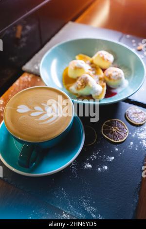 Frischer Kaffee mit Käsepfannkuchen mit Banane, Erdnussbutter und Himbeersoße Stockfoto