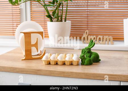 Halter mit Ostereiern und Kaninchen auf Küchentisch Stockfoto