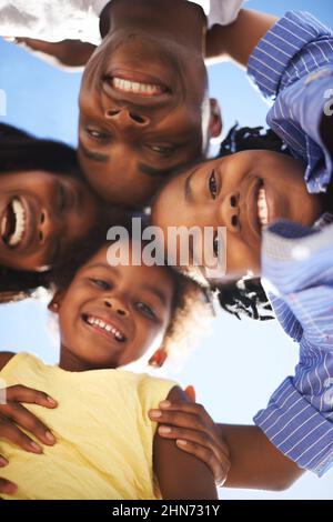 Die Köpfe zusammenfügen. Low-View-Porträt einer glücklichen afroamerikanischen Familie, die gemeinsam den Tag am Strand verbringt. Stockfoto