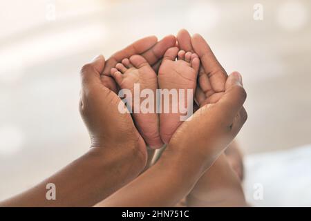 Gehen Sie vorsichtig damit um. Kurzer Schuss einer Mutter, die ihre Babys Füße hält. Stockfoto