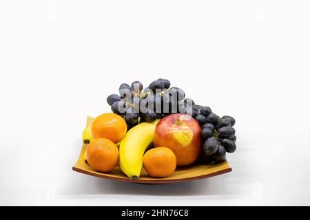 Stillleben einer Bambusplatte gefüllt mit frischen Früchten als Hintergrund mit Kopierraum. Stockfoto
