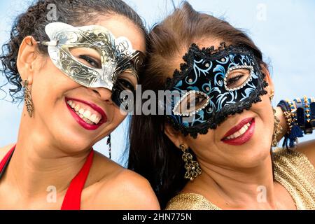 Nahaufnahme des Gesichts von zwei Frauen, die die Karneval-Maske von Venedig vor hellem Hintergrund tragen. Salvador, Bahia, Brasilien. Stockfoto