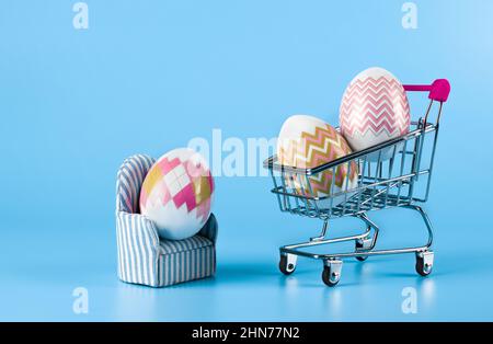 Die Idee der Lieferung von Einkäufen zu Ostern nach Hause, auf blauem Hintergrund Stockfoto