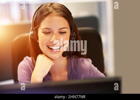 Protokollieren aller Anrufe, die sie erhält. Eine kurze Aufnahme einer jungen Geschäftsfrau, die ein Headset an ihrem Schreibtisch trägt. Stockfoto