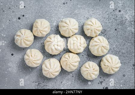 Gefrorene, ungekochte Baozi-Knödel, gefüllt mit Fleisch. Grauer Hintergrund. Draufsicht Stockfoto