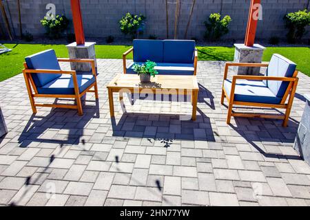 Terrasse mit hinteren Pflastermöbeln, Sofa, Tisch und zwei Stühlen Stockfoto