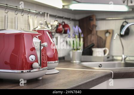 Roter Toaster und Wasserkocher im Retro-Stil auf der Tischplatte im Kücheninnenraum. Stockfoto