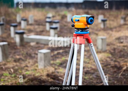 Vermesser, Theodolit oder total Positioning Station auf der Baustelle. Foundation arbeitet mit dem Fahren von Stapeln Stockfoto