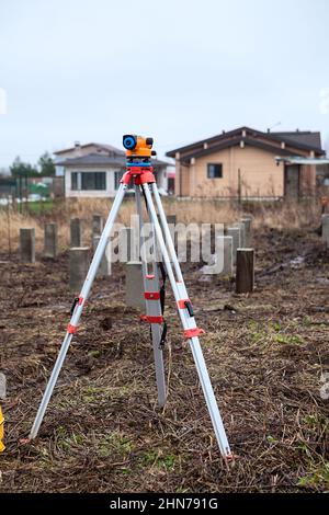 Theodolit steht auf einem Stativ in der Mitte der Baustelle, Fundamente, niemand Stockfoto