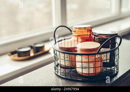 Set von Kerzen in verschiedenen Glas- und Metallgefäßen in der Nähe des Fensters Stockfoto