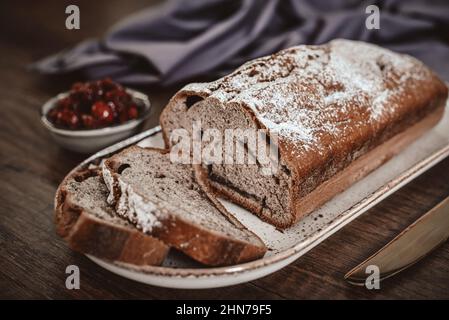 Frisch gebackener Kuchen auf dem Teller mit einer Tasse Tee und Kirschmarmelade aus der Nähe Stockfoto