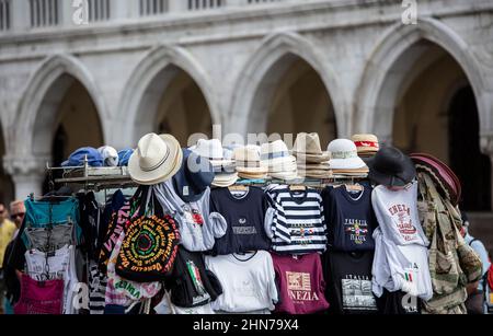 Straßenstände auf dem Platz st Marks, die Venationsmasken und T-, T- und T-Shirts sowie Hüte verkaufen, die sich an die vielen Touristen richten, die jedes Jahr nach Venedig strömen Stockfoto