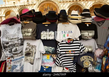 Straßenstände auf dem Platz st Marks, die Venationsmasken und T-, T- und T-Shirts sowie Hüte verkaufen, die sich an die vielen Touristen richten, die jedes Jahr nach Venedig strömen Stockfoto