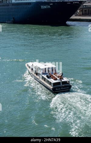 Die großen Kreuzschiffe, die täglich auf Venedig abfahren und mit ihnen Massen eifriger Touristen mit Wassersteuer von Schiff zu Land bringen Stockfoto