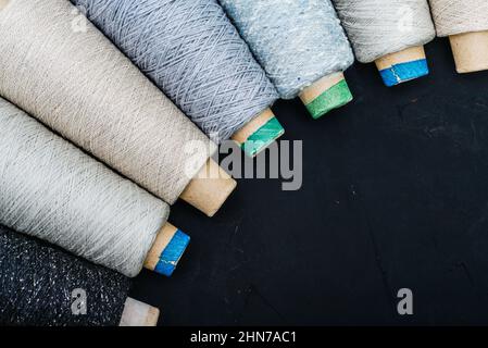 Set aus farbigem Garn zum Stricken auf Kegel auf schwarzem Hintergrund, Draufsicht Stockfoto